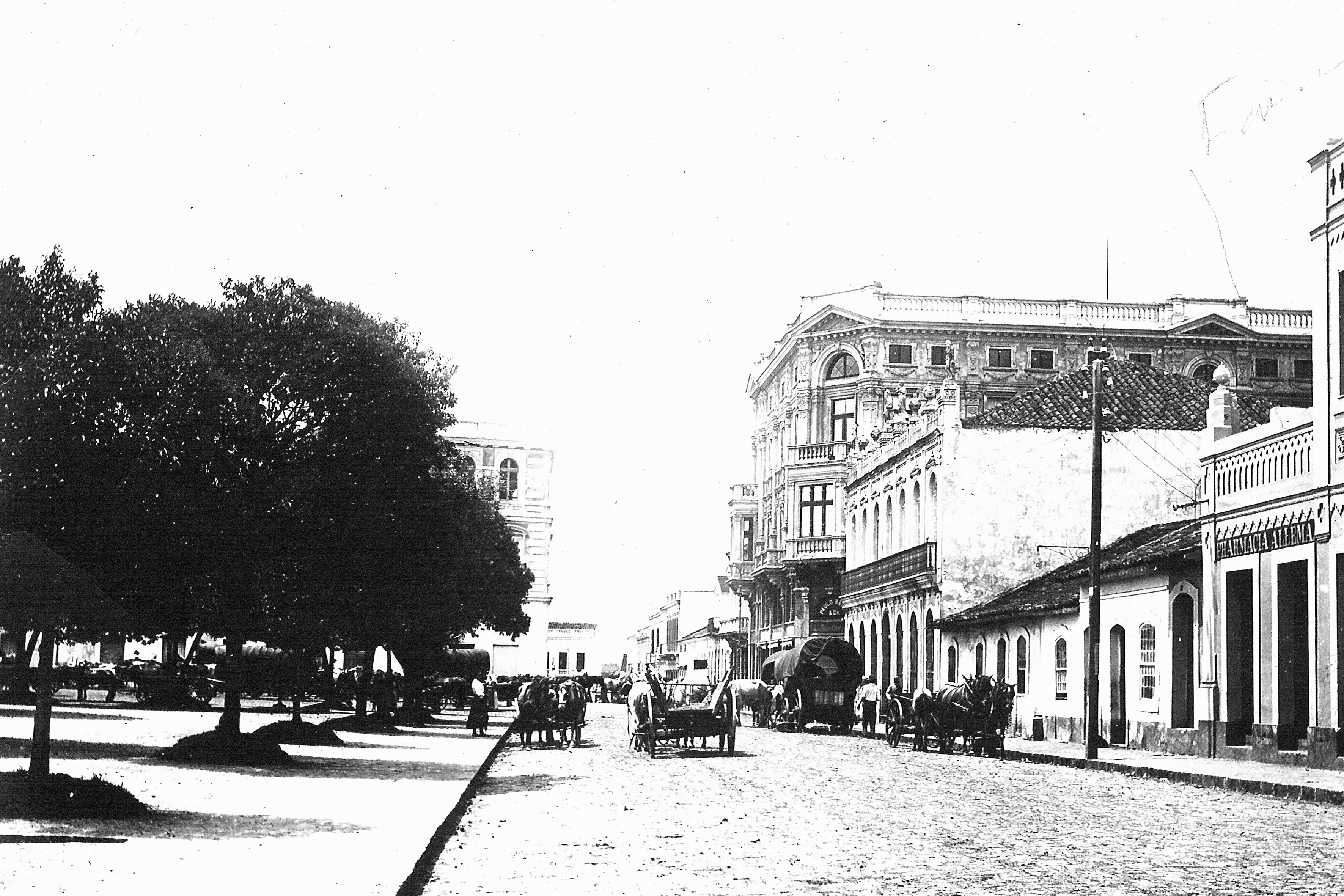 Praça Tiradentes, em 1910. O local encontra-se urbanizado, apresentando passeios e leito da rua delimitados e pavimentados, além poste de iluminação pública. A praça apresenta uma arborização consolidada.